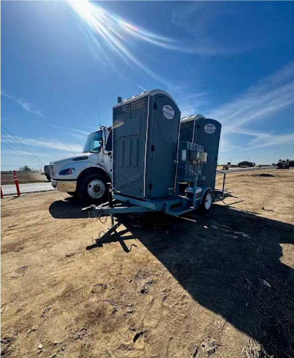 A clean, well-maintained double mounted trailer with a handwashing station on a Bakersfield agricultural site.