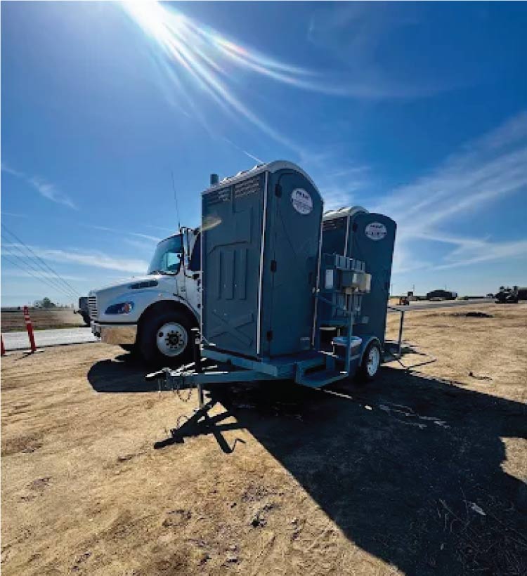 Standard portable toilet unit providing basic sanitation needs on a busy construction site